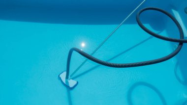 Havuz temizleme hortumu ve vakum başı berrak mavi suya batırılmış..