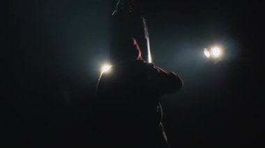 Dövüşçülerin silueti, spor salonundaki üçlü boks armuduna çarpıyor..