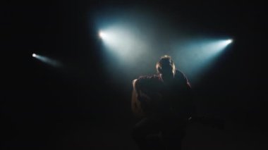 Genç bir müzisyen sahne ışığında sahnede gitar çalar. 4k video