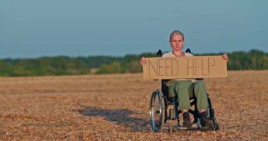 Orta yaşlı bir kadın tekerlekli sandalyede oturuyor ve elinde üzerinde 