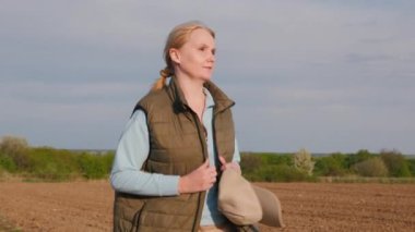 Bir kadın çiftçi tarlaların arasında köy yolunda yürüyor..