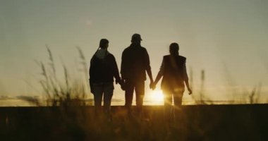 Genç mutlu aile el ele tutuşuyor, gün batımını seyrediyorlar, bir tarlanın üzerinde, dikiz aynasından..