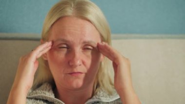 Orta yaşlı bir kadın yatakta oturuyor, şaşkınlık ve neşe içinde gülüyor, sıcak ve neşeli bir atmosfer yaratıyor. Yüksek kalite 4k görüntü