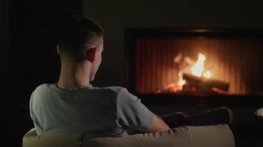 Arkadan parlayan bir şömineye bakan genç adam. Yüksek kalite 4k görüntü