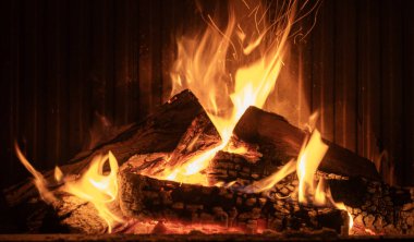 Vivid flames and glowing embers burning through stacked firewood in a fireplace, with sparks rising, creating a warm and inviting indoor ambiance. High quality photo