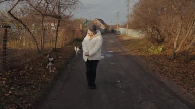 Genç bir kadın, başıboş köpeklerle çevrili dar, ürkütücü bir sokakta duruyor. Kafası karışmış ve ne yapacağından emin olmayan bir şekilde bakıyor. Yüksek kalite 4k görüntü