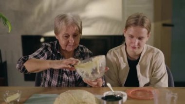Sevgi dolu bir büyükannenin torunuyla keyifli bir yemek pişirme anını paylaşması, yemek hazırlama sevincini ve değerli ailelerinin paha biçilemez değerini vurgulaması, iç açıcı bir sahnedir.