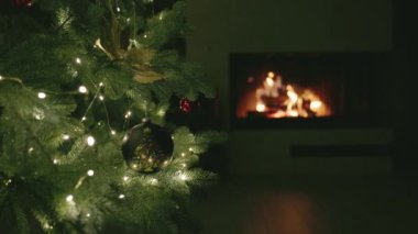 Arka planda parlayan bir şömine ile aydınlatılmış, boyalı bir ağacın yer aldığı bir Noel ağacı dalının yakın çekimi. Yüksek kalite fotoğraf