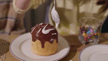 Süslü bir Paskalya pastasına yakın plan, üzerine beyaz krema serpiştirilmiş ve yanında renkli şekerler serpiştirilmiş. Yüksek kalite 4k görüntü