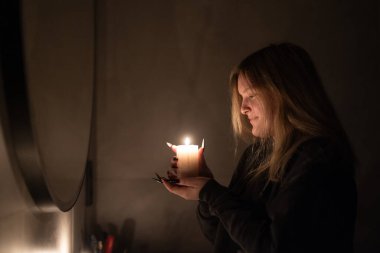 A young woman smiles softly while holding a lit candle, its warm glow illuminating her face. The serene atmosphere highlights her peaceful and reflective mood. High quality photo clipart