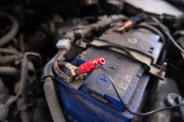 Kırmızı kablosu olan bir araba aküsünün yakın çekimi, elektrik tamiri ve araç bakımı yapılıyor. Yüksek kalite fotoğraf