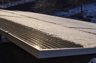 Yerleşim yerinin çatısındaki kar tozlu güneş panelleri güneş ışığının yüzeye yansımasıyla kış enerjisini tasarruflu bir çözelti sunuyor. Yüksek kalite fotoğraf