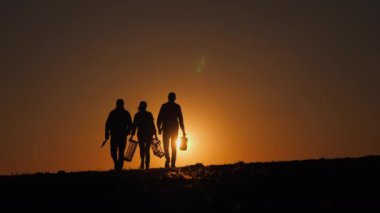 Çarpıcı bir günbatımında siluete bürünmüş bir grup çiftçi, kırsal hayattaki birliği yansıtan alet ve sandıklarla sahadaki takım çalışmasını ve bağlılığı sembolize ediyor.