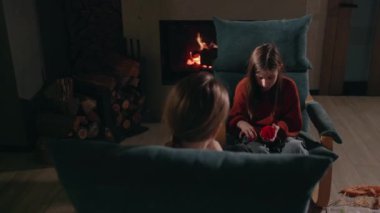İki kız sıcak ve huzurlu bir ortam yaratmak için şöminenin yanında örgü örüyor. Yüksek kalite 4k görüntü