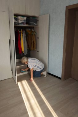 Yaşlı bir kadın evdeki gardırobu sprey şişeyle temizliyor, gündüzleri odayı düzenliyor. Yüksek kalite fotoğraf