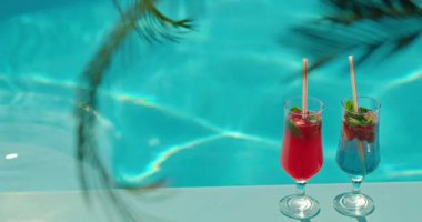 Çilekli iki renkli kokteyl ve turkuaz havuzlu nane şekeri ferahlatıcı ve tropikal bir yaz havası yaratıyor. Yüksek kalite 4k görüntü