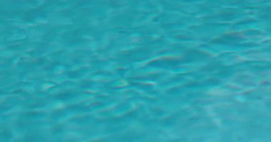 Açık mavi bir havuzun yüzeyinde hafif dalgalanmalar, arka plan ve dokular için dingin su desenleri sergiliyor. Yüksek kalite 4k görüntü