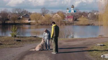 Yaşlı bir kadın ve torunu, manzaralı bir gölün yanında Golden Retriever 'larıyla yürüyüşe çıkıyorlar. Genç adam tasmasını tutarken kadın köpeği sevgiyle okşar. Bir kilise ve kırsal evler