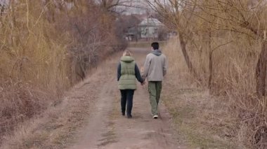 Genç bir çift bulutlu bir bahar gününde kirli bir patika boyunca el ele yürür. Onlar kuru çimenler ve çıplak ağaçlarla çevrili, sıcak giysiler giyiyorlar ve önünde küçük bir köpek koşuyor. Yüksek kalite 4k