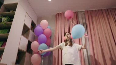 Pembe perdelerin yanında pembe kulaklık takmış, elinde renkli balonlar tutan genç bir kız. Yüksek kalite 4k görüntü