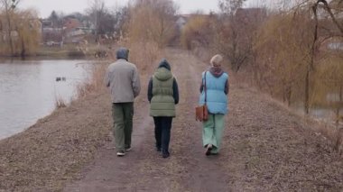 Genç bir çift bulutlu bir bahar gününde anneleriyle birlikte göl kenarında kirli bir patika boyunca yürür. Sıcak giyinmişler, etrafları çıplak ağaçlar ve sazlıklarla çevrili. Huzurlu bir aile gezintisi yapıyorlar.