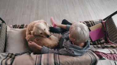 Kıdemli kadın salıncakta dinlenirken Golden Retriever 'ını nazikçe tımar ediyor. Köpek mutlu ve sakin görünüyor, şefkatli bakımın tadını çıkarıyor. Yüksek kalite 4k görüntü