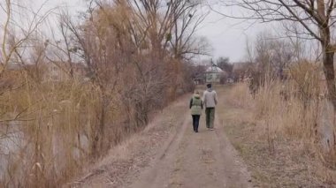 Genç bir çift, bulutlu bir bahar gününde kırsal bir toprak yolda el ele yürür. Kuru otlar ve çıplak ağaçlarla çevrili kalın giysiler giyerlerken, küçük bir köpek önde koşuyor. Yüksek