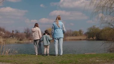 Sakin bir gölün yanında el ele duran üç kız, kırsal bir köyde huzurlu bir bahar gününün tadını çıkarıyorlar. Yüksek kalite 4k görüntü