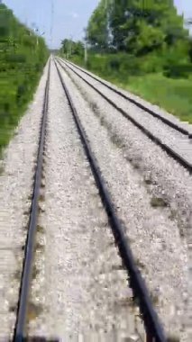 Güneş batarken kırsal bir köyde tren yolu kıvrılıyor. Elektrik hatları ve parlayan gökyüzünün altında dağınık evler var. Yüksek kalite 4k görüntü