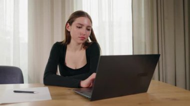 Evde dizüstü bilgisayarda çalışan genç bir kadın. Ahşap masaya odaklanmış ve odaklanmış. Yüksek kalite 4k görüntü