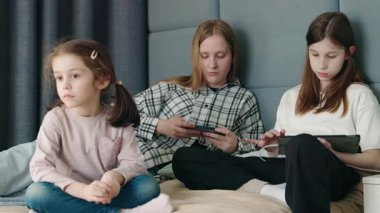 Genç bir kız yanında oturup dışlanmış ve görmezden gelinmiş hissederken iki genç kız aletlere dalmış. Yüksek kalite 4k görüntü