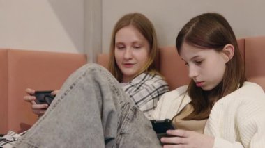 İki genç kız bir yatakta uzanıyorlar ve aletlerine gömülüyorlar. Biri akıllı bir telefonla, diğeri de ekranlarına odaklanmış bir masayla, rahat bir ortamda.