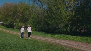 İki yaşlı kadın merdivenlerden çıktıktan sonra sessiz bir parkta yan yana yürüyor, biri rehabilitasyonunun bir parçası olarak özenle yürüyor. Yüksek kalite 4k görüntü