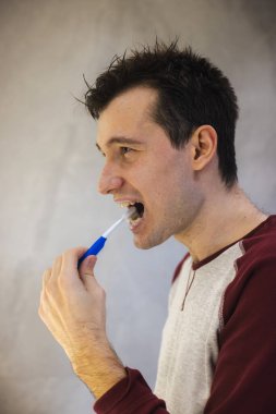 Genç adam dişlerini dikkatlice fırçalıyor, ağız hijyenini koruyor ve düzenli bir kişisel bakım rutininin parçası olarak diş sağlığını destekliyor.