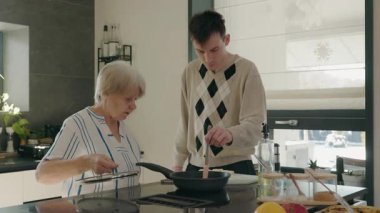 Büyükannem ve torunum parlak bir mutfakta ev yapımı süzme peynirli krep yapıyorlar.. 