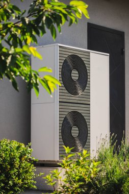 Ev ısıtma ve soğutma için modüler ısı pompası. Dekoratif bitkiler ve bahçe düzenlemeleriyle çevrili bir duvarın yanına kurulmuş. Yüksek kalite fotoğraf