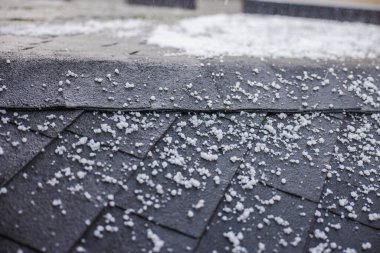 Bir dolu fırtınası sırasında kiremitleri olan siyah bir çatıya saçılmış küçük dolu taşlarının yakın çekimi. Yüksek kalite fotoğraf