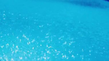 Şiddetli yağmur sırasında mavi bir yüzme havuzunun yüzeyine düşen yağmur damlalarının yakın çekimi. Yüksek kalite 4k görüntü