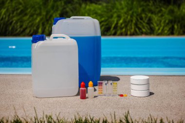 Havuz başında büyük kimyasal kaplar, test kiti, damlatıcı şişeleri ve havuz bakımı ve su kalite kontrolü için kullanılan klor tabletleriyle düzenleme. Yüksek kalite fotoğraf