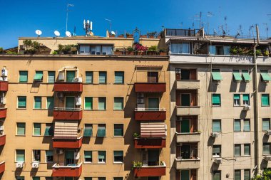 İtalya, Roma 'da açık mavi gökyüzü altında balkonları, bitkileri ve antenleri olan apartman binaları. Yüksek kalite fotoğraf