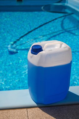 Havuz kenarında duran bir vida kapaklı mavi kimyasal kap, yaz aylarında havuz suyunun berraklığını dezenfekte etmek ve muhafaza etmek için kullanılır. Yüksek kalite fotoğraf