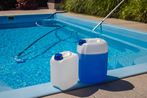 Havuz kenarına havuz temizleme için iki kimyasal teneke kutu, güneşli bir günde arka planda vakum hortumu ve temiz mavi su. Yüksek kalite fotoğraf