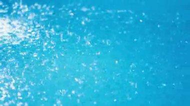 Şiddetli bir yaz yağmuru sırasında açık mavi bir yüzme havuzunun yüzeyine yağmur damlaları sıçrıyor. Yüksek kalite 4k görüntü