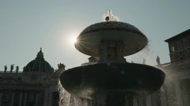 Vatikan, Roma ve İtalya 'da güneş ışığı ve bazilika kubbesiyle St. Peters Meydanı' nda akan suyla çeşme..