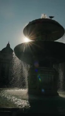 St. Peters Meydanı 'nda arkaplanda bazilika kubbesi, Vatikan Şehri, Roma ve İtalya' da güneş ışığıyla akan çeşme..