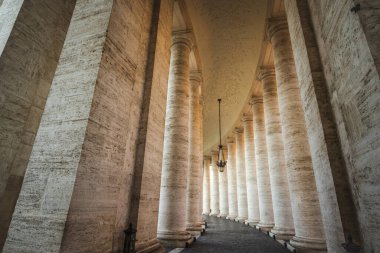 Vatikan 'ın St. Peters Meydanı' nda büyük taş sütunlar ve asılı fenerlerle kavisli sütunlar büyük bir mimari perspektif yaratıyor. Yüksek kalite fotoğraf
