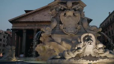 Roma 'daki Pantheon' un önündeki aydınlık fıskiyenin akşam manzarası akan su ve ayrıntılı heykellerle. Yüksek kalite 4k görüntü