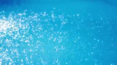 Parlak yağmur damlaları, yoğun yağmur altında turkuaz havuz yüzeyine yayılarak yakın çekim görüntüsünde parıltılı sıçramalar oluşturur. Yüksek kalite 4k görüntü