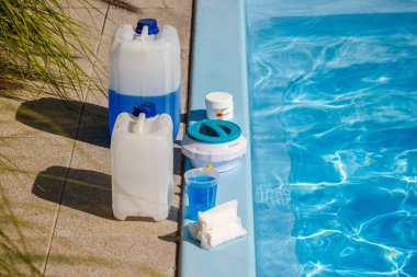 Kimyasal kutularla yüzme havuzu bakım seti, klor tabletleri, yüzer vazo, mavi sıvıyla ölçme kabı ve havuz kenarına temizlik malzemeleri. Yüksek kalite fotoğraf
