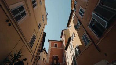 Sıcak renkli binalar ve açık panjurlarla dar Roma caddeleri yukarı doğru güzel bir bakış açısı yaratıyor. Yüksek kalite 4k görüntü